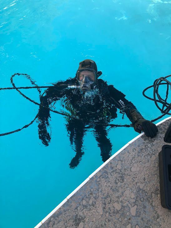 A man in a scuba suit is swimming in a pool