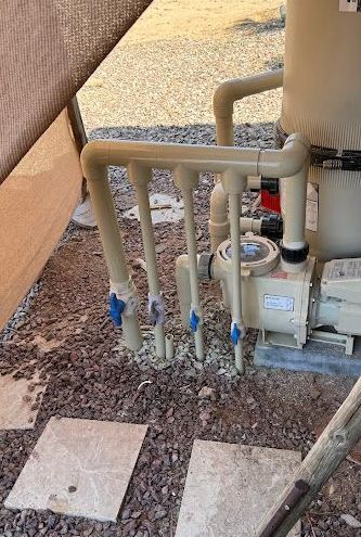 A swimming pool pump is sitting on top of a pile of gravel.