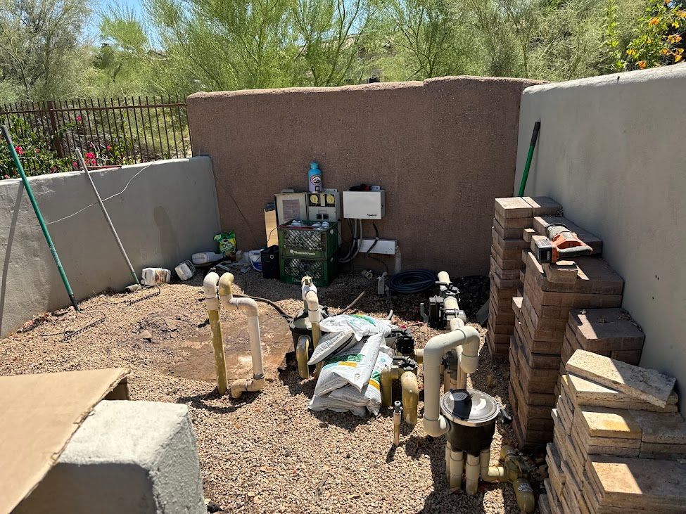 A pile of bricks is sitting on the ground in a backyard next to a wall.
