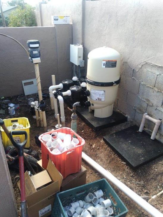 A swimming pool filter is sitting on top of a pile of pipes.