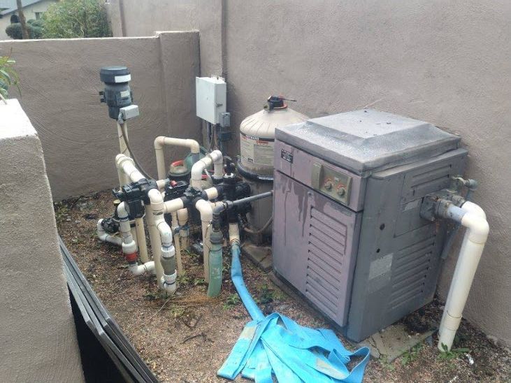 A swimming pool heater is sitting on the ground next to a wall.