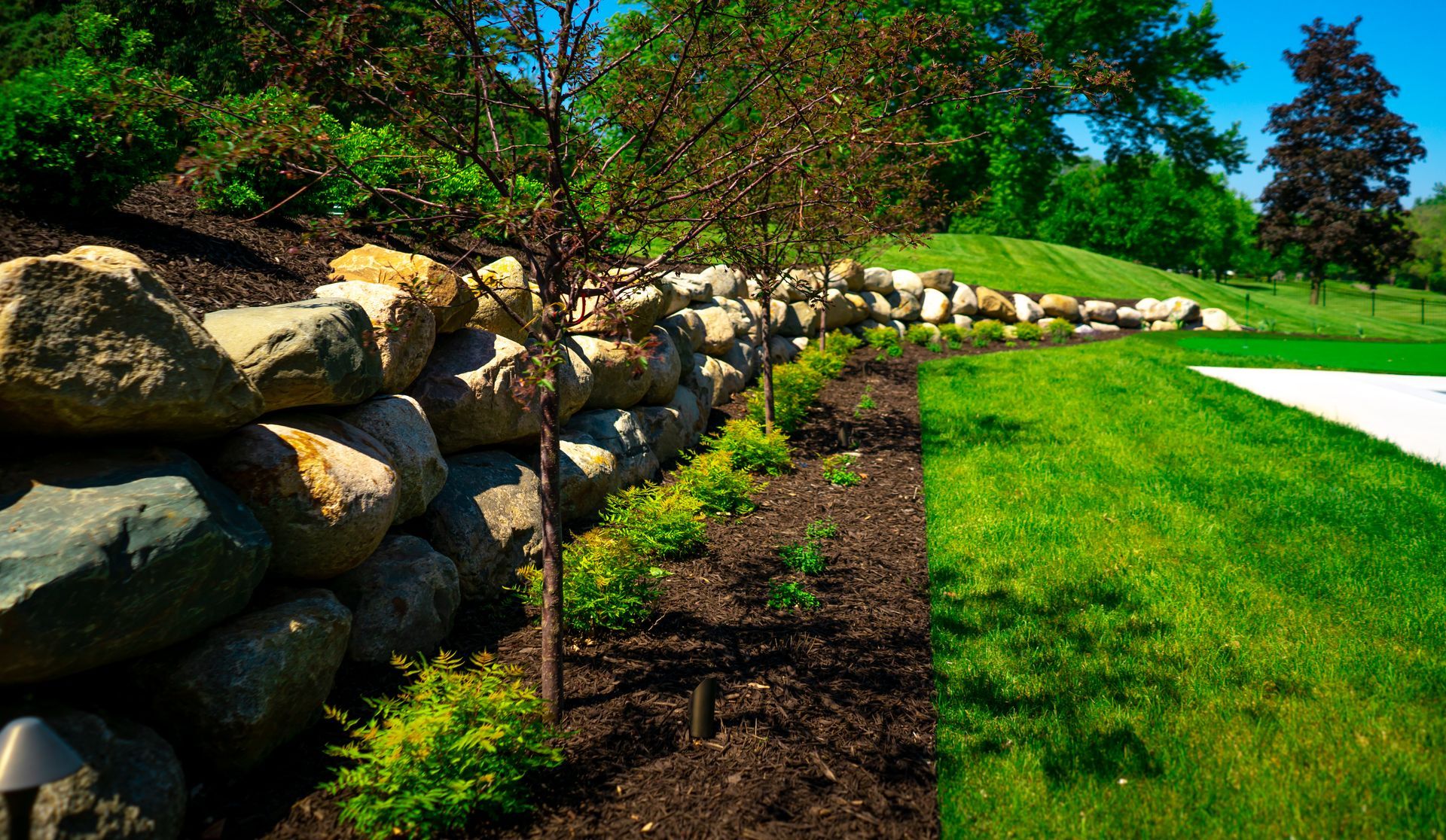 A stone wall surrounds a lush green lawn.