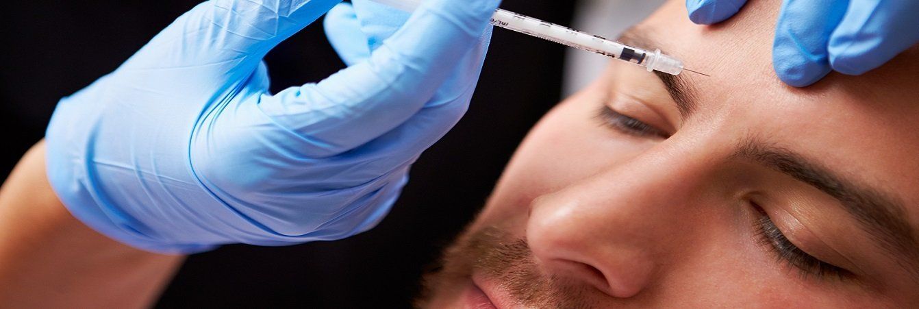A man is getting a botox injection in his forehead.