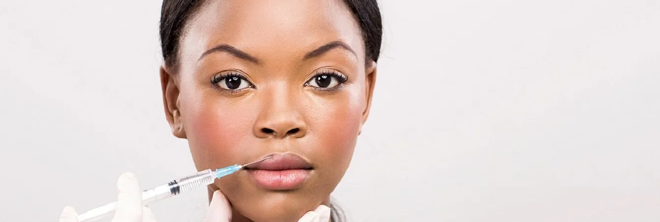 A woman is getting a botox injection in her lips.