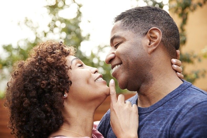 A woman is kissing a man on the cheek.
