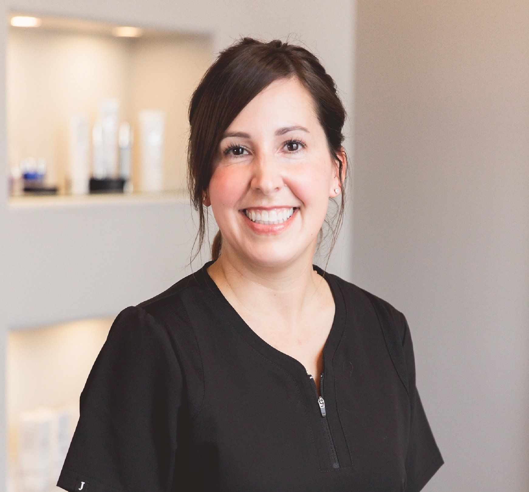 A woman in a black scrub top is smiling for the camera