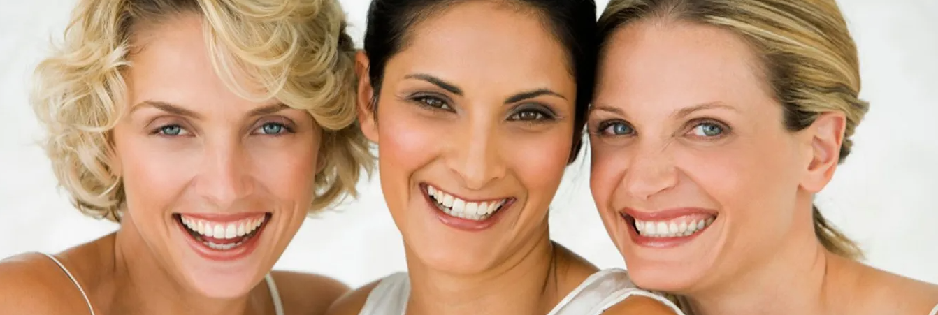 Three women are posing for a picture and smiling for the camera.