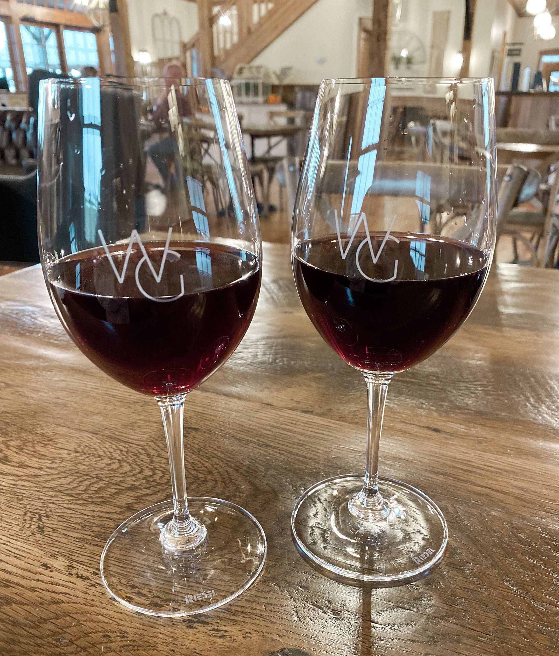 Two glasses of red wine are sitting on a wooden table. Two glasses of red wine are sitting on a wooden table.