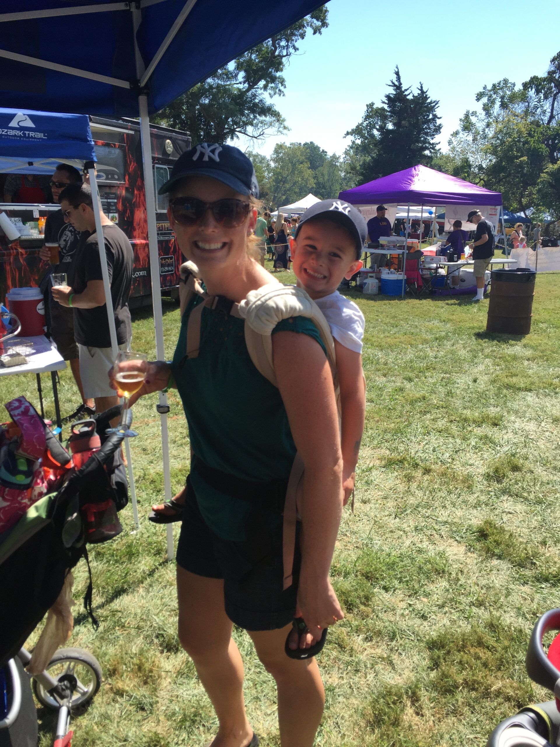 A woman is carrying a child on her back in a park. A woman is carrying a child on her back in a park.