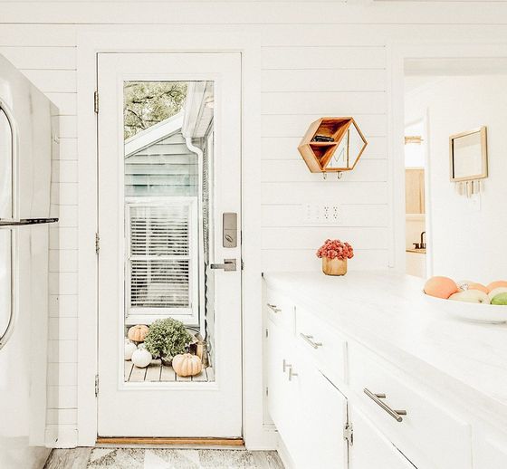 A kitchen with white cabinets , a washer and dryer , and a glass door.