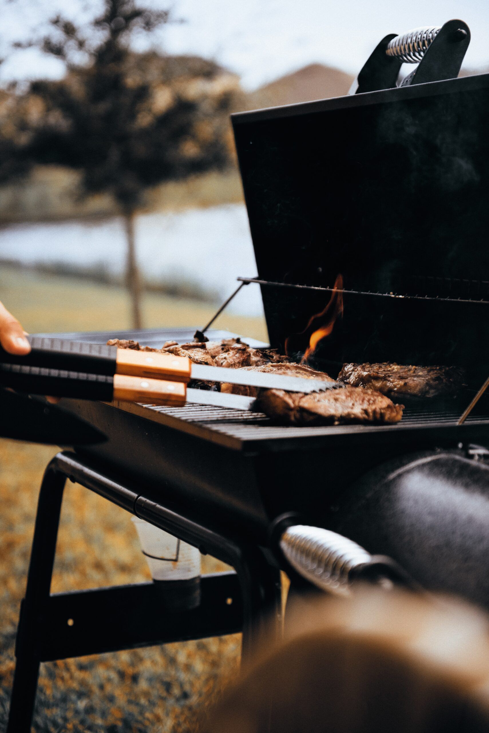 A person is cooking meat on a grill outside. A person is cooking meat on a grill outside.