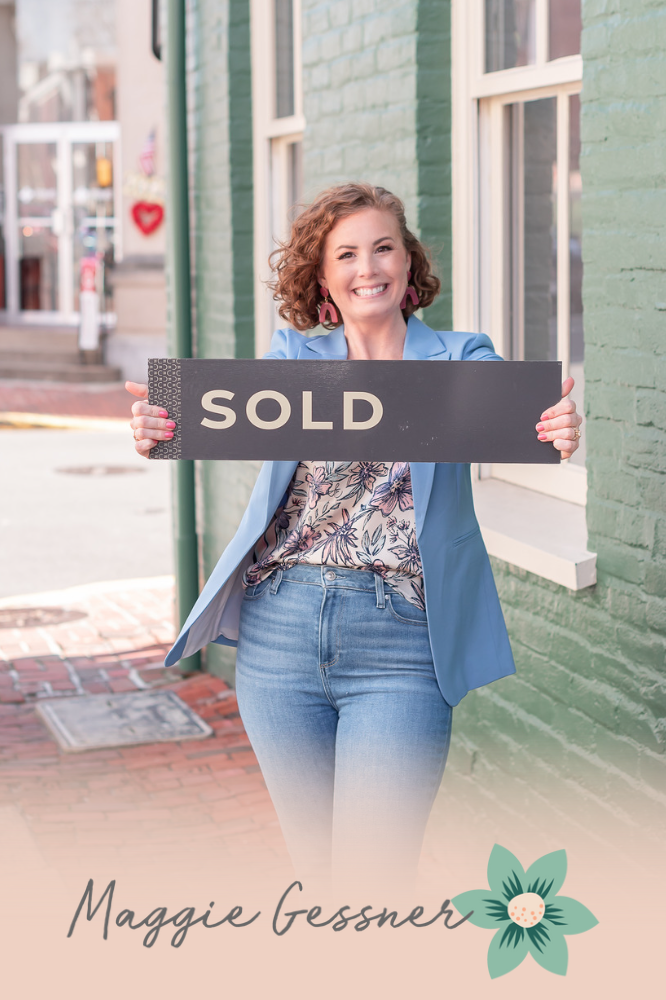A woman is holding a sold sign in front of a brick building. A woman is holding a sold sign in front of a brick building.