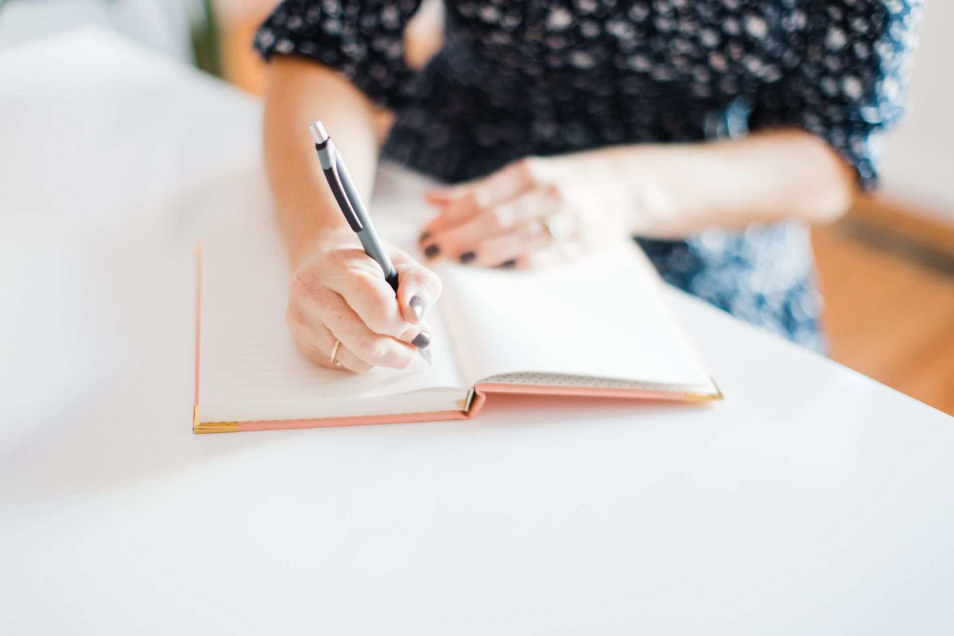 A woman is writing in a notebook with a pen. A woman is writing in a notebook with a pen.