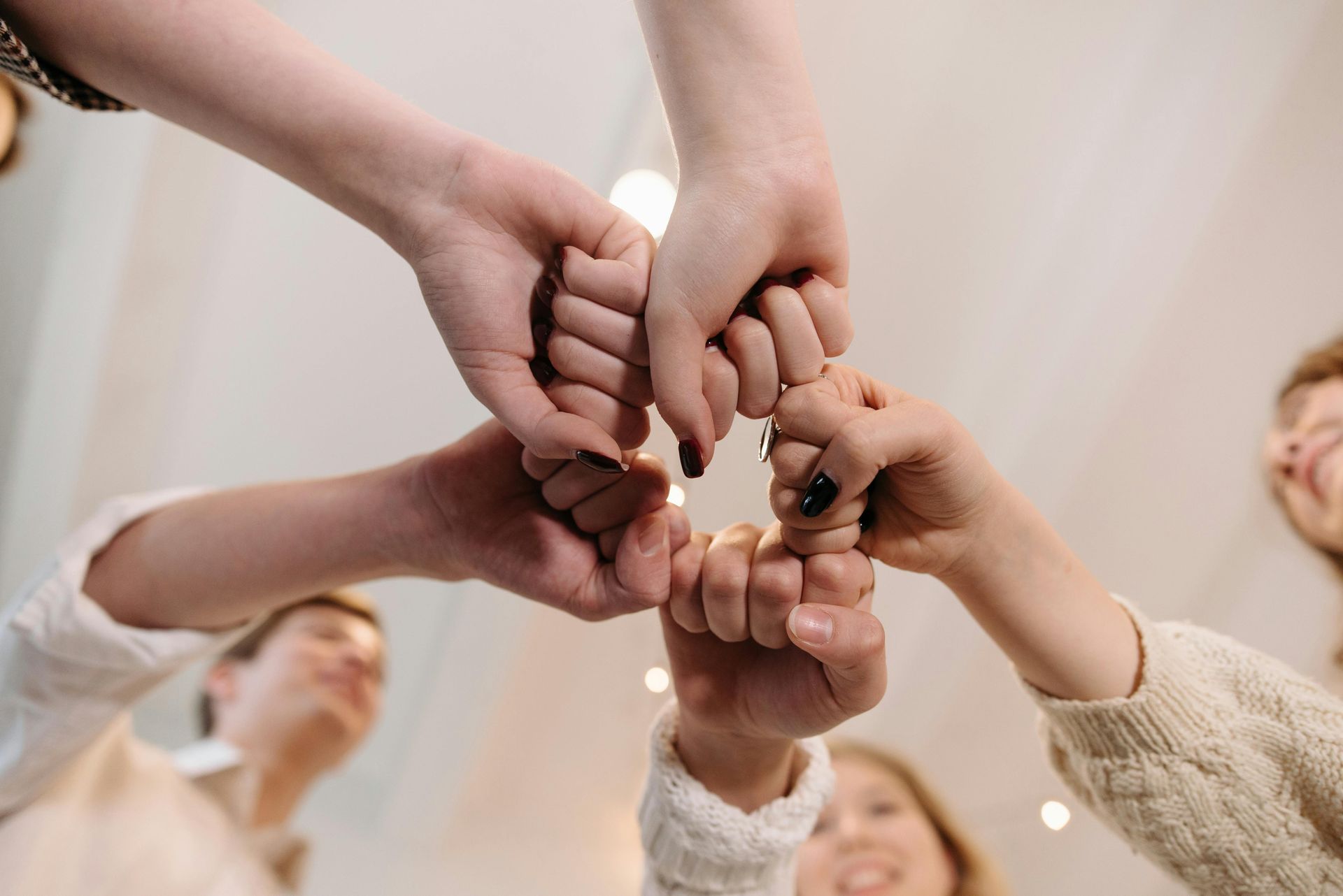 A group of people bringing their fists together in a center circle to show unity and teamwork.