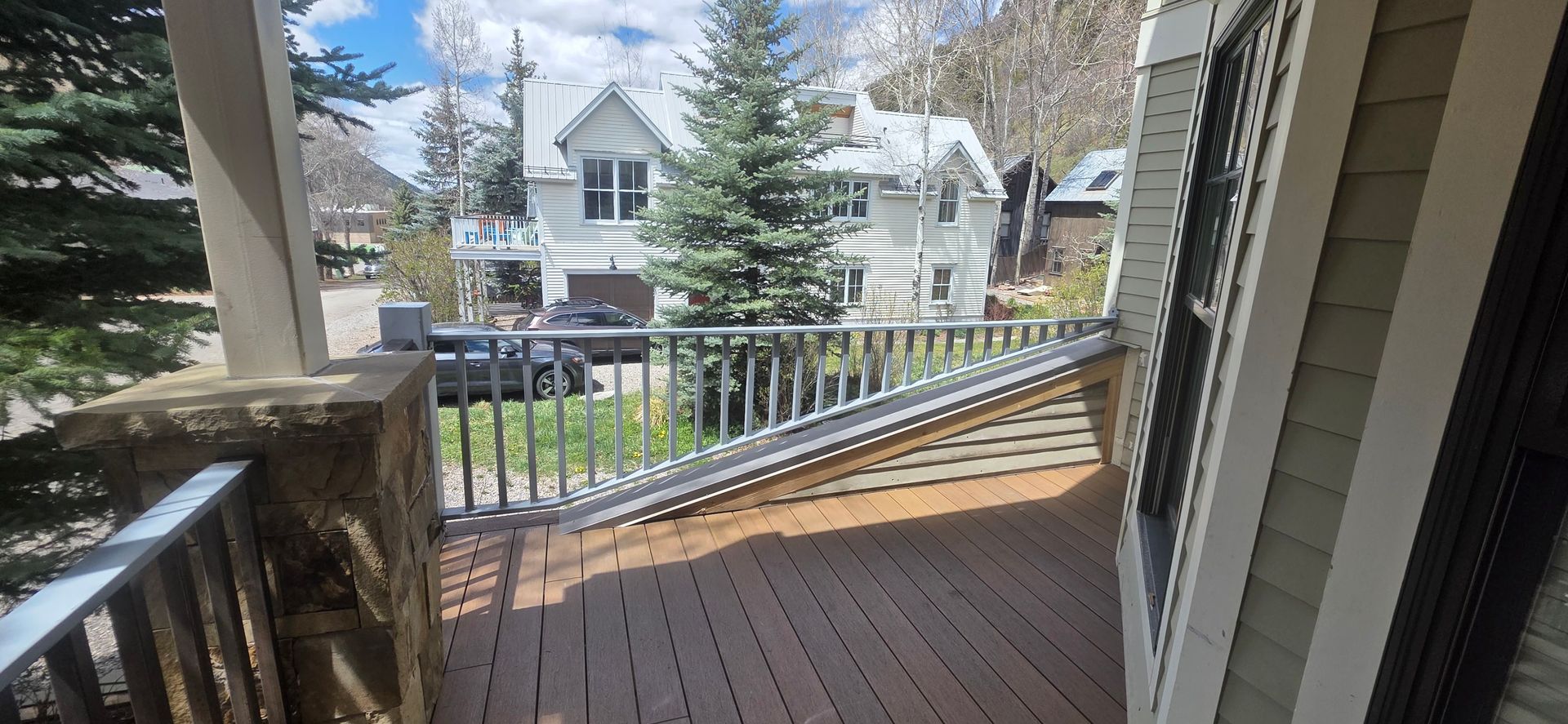 Porch with wooden railing and ramp overlooking a residential street and houses across the way