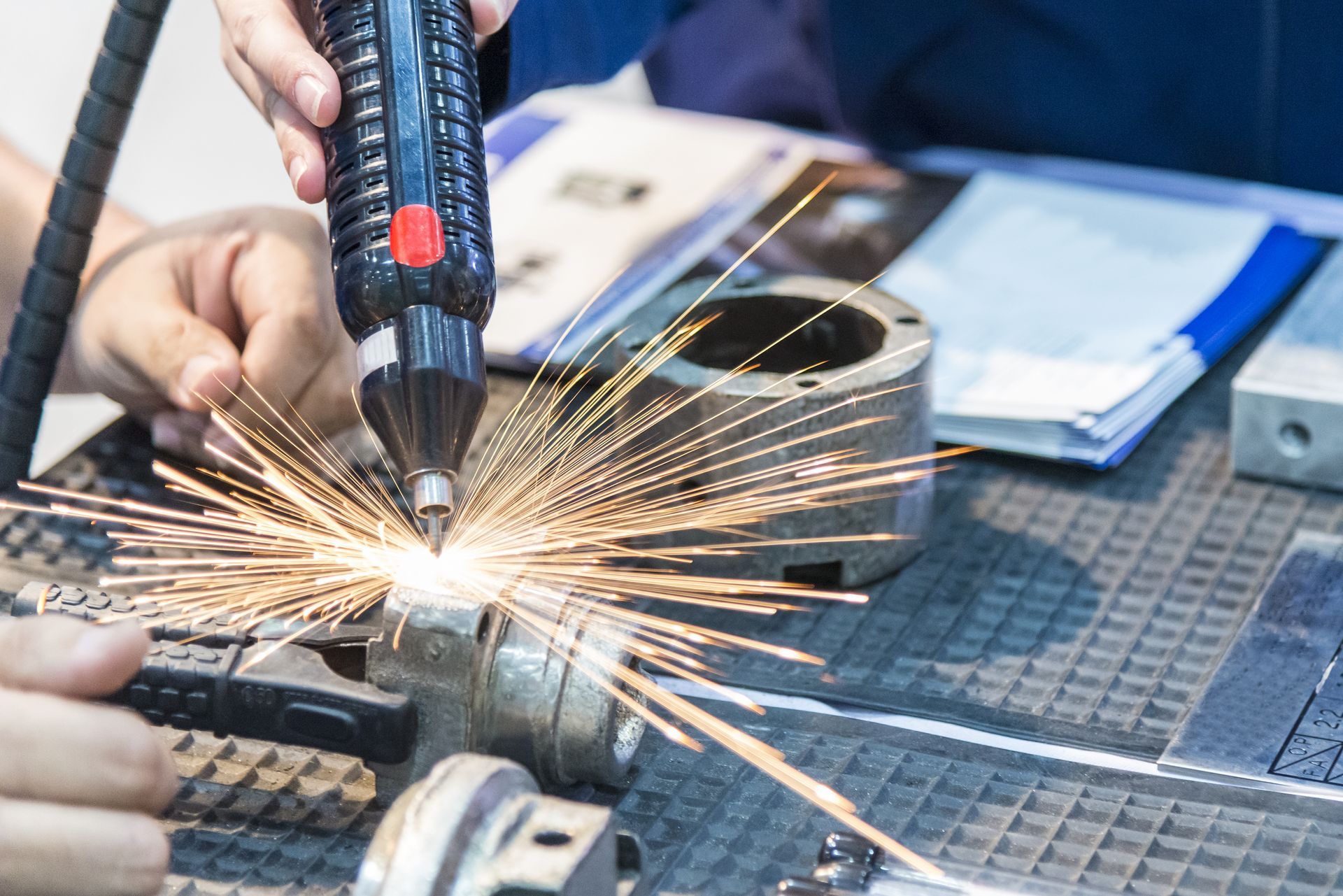 Person welding metal on a workbench, sparks flying in a workshop.
