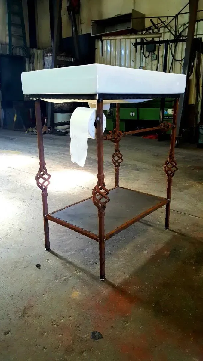 Rustic metal sink stand with a white basin in a workshop-like space