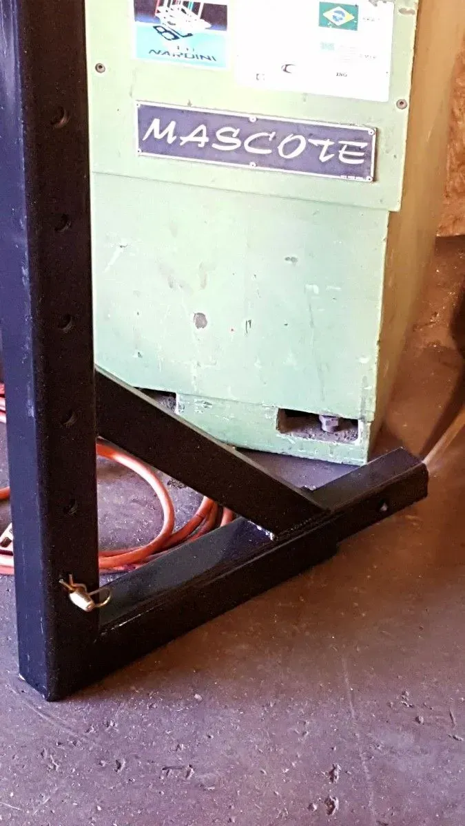 Mint-green Mascote machine behind a black frame on a concrete floor, with a hose nearby.