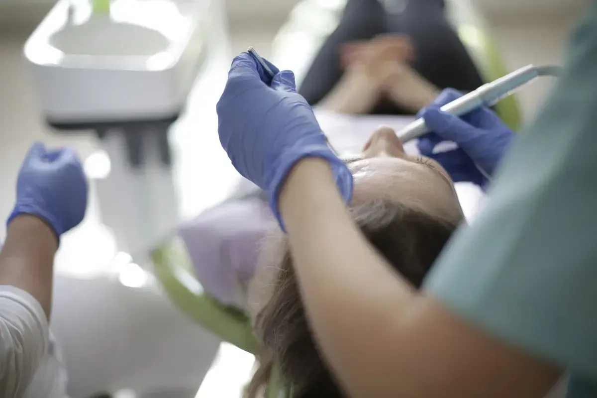 Tandlæge udfører en procedure på en patient i en tandlægestol.