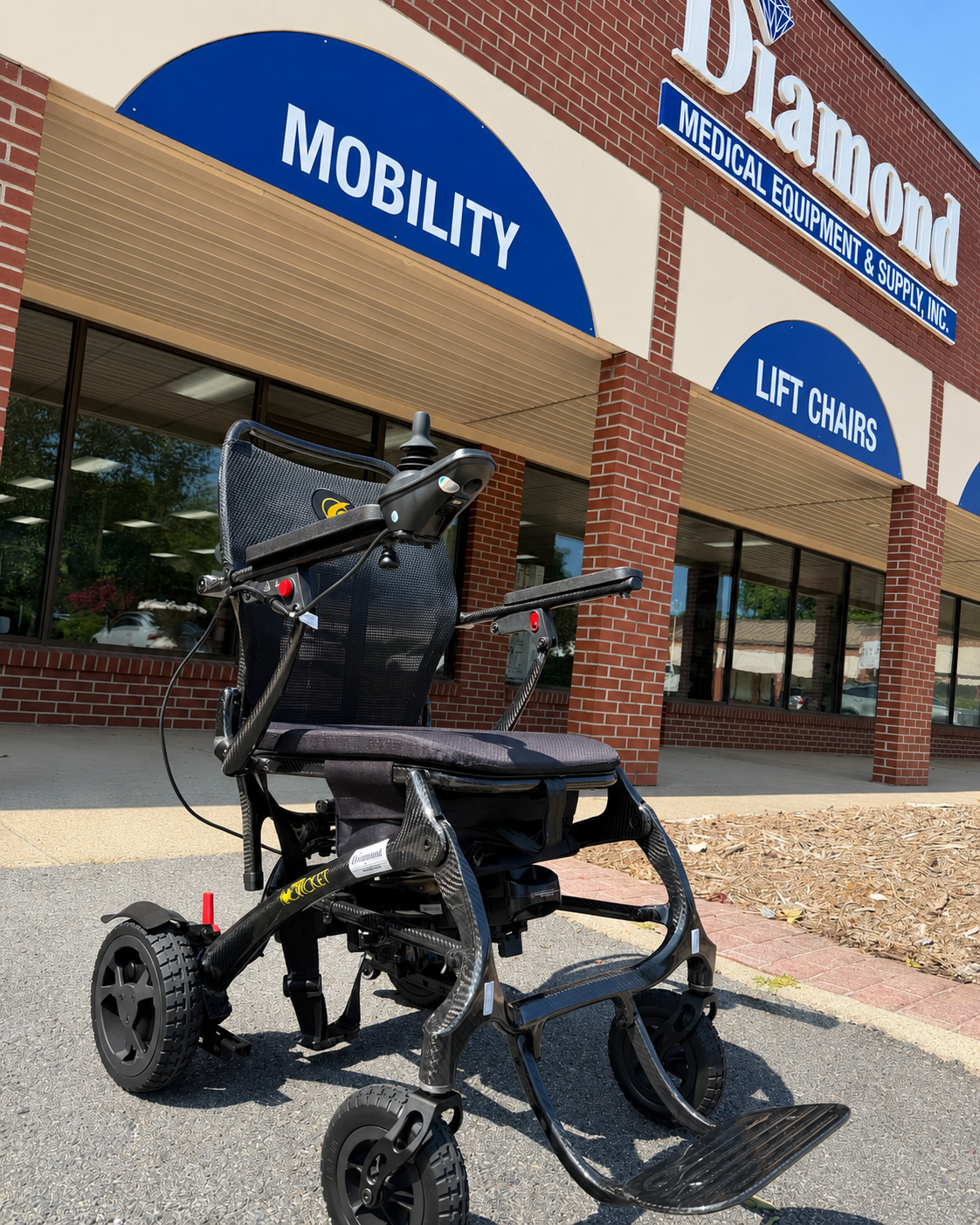 Black mobility scooter parked outside Diamond Medical's entrance with MOBILITY and LIFT CHAIRS signs.