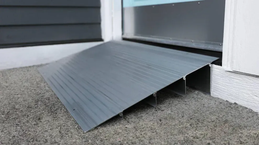A gray metal threshold ramp providing a gentle slope for wheelchair access at a doorway entrance.