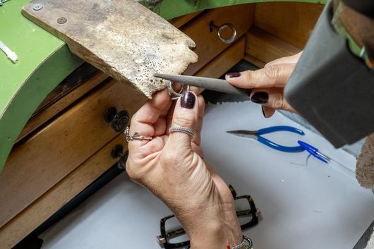 Mani di un orafo al banco da lavoro