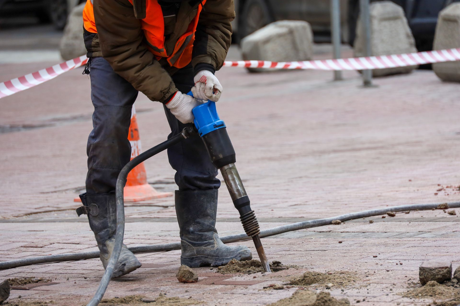 A construction worker is using a hammer to drill a hole in the ground.