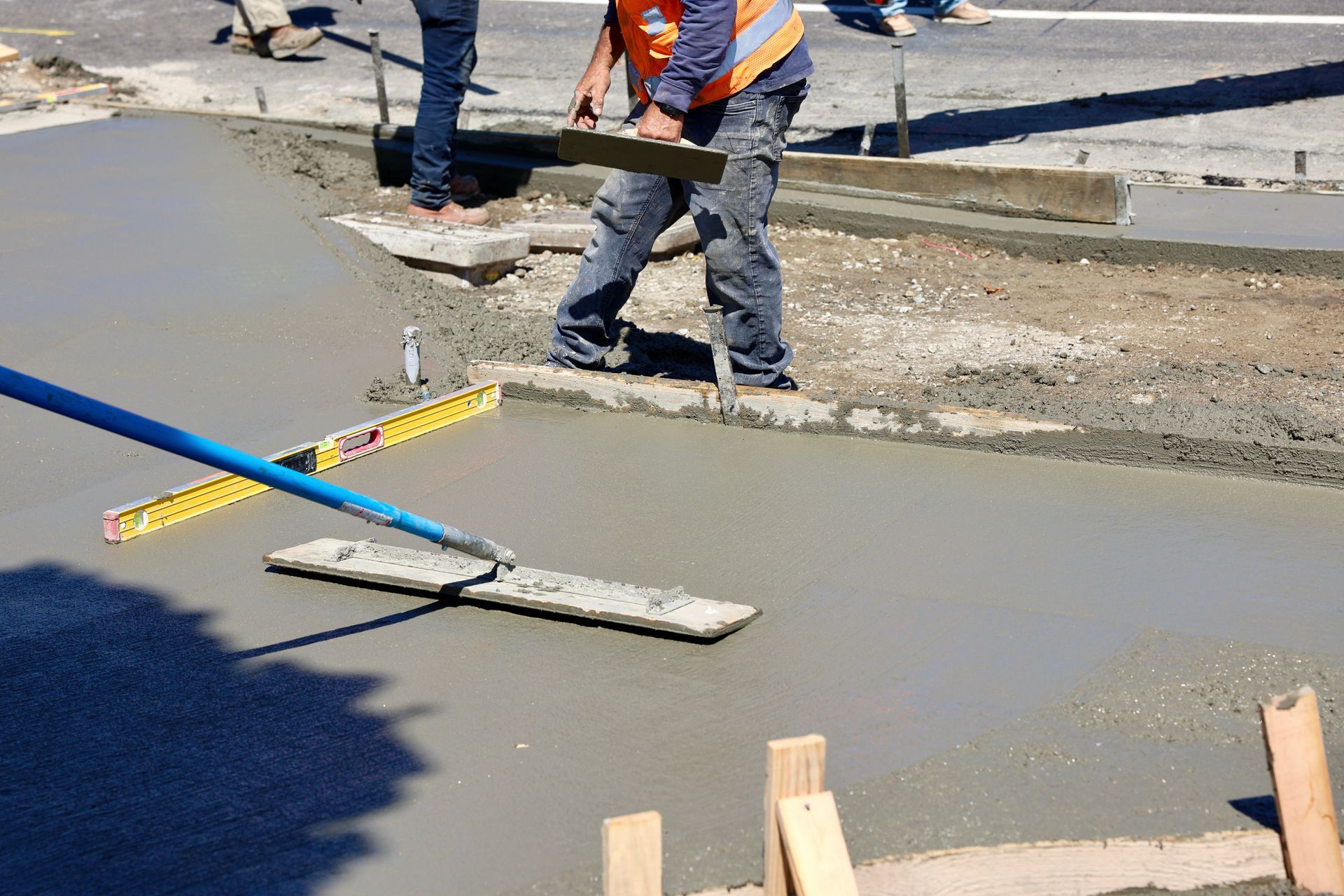 A construction worker is leveling a concrete surface with a level.