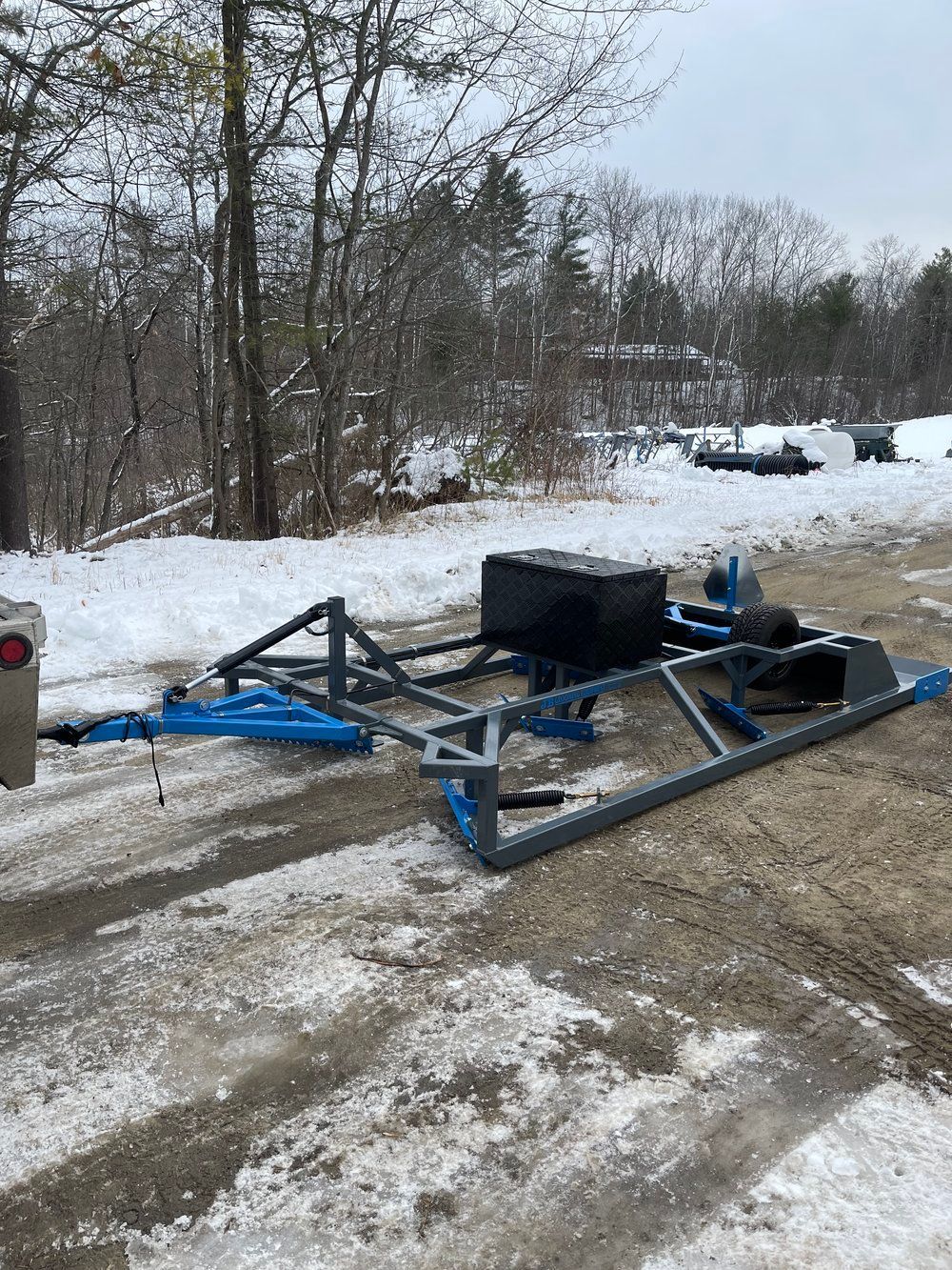 A trailer is sitting on the side of a snow covered road.