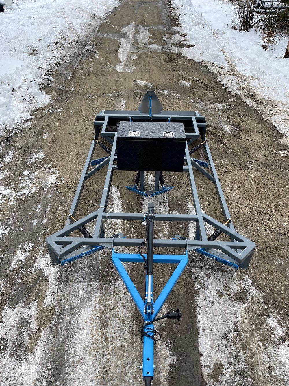 A trailer is sitting on a dirt road in the snow.