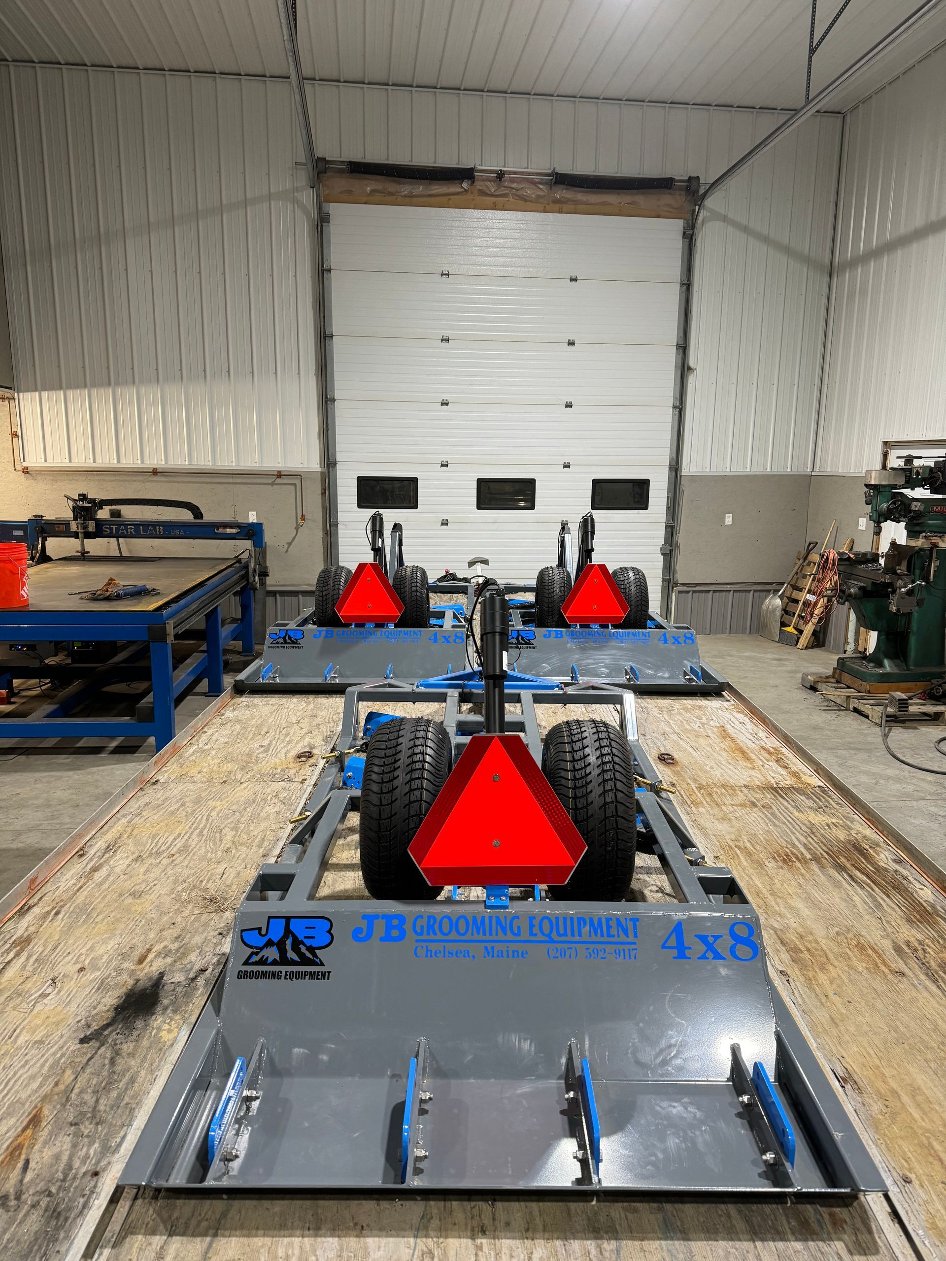 A row of tractors are sitting in a garage.