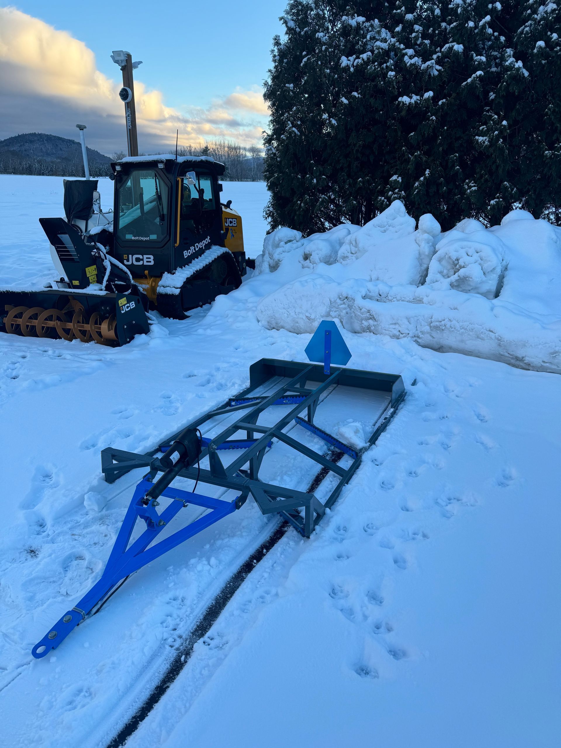 A snow plow is parked in the snow next to a sled