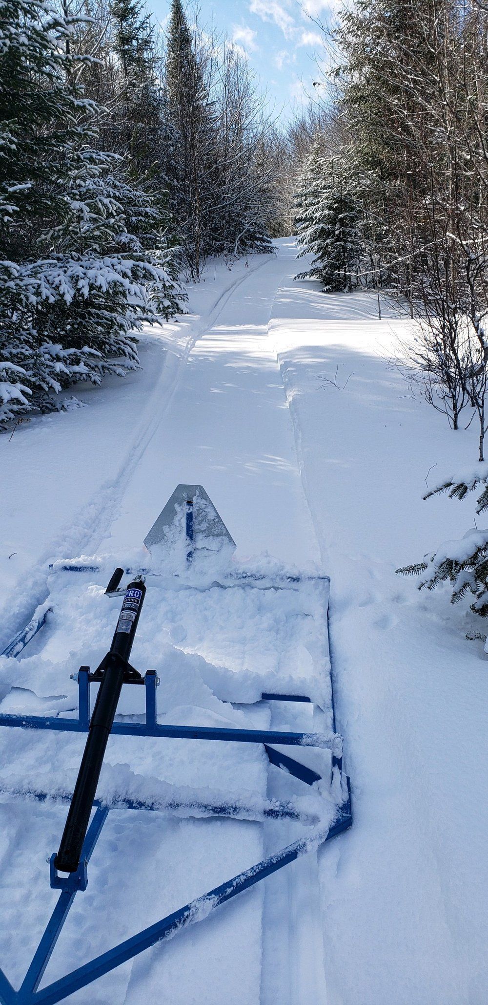 A snowmobile is pulling a sled down a snowy road.