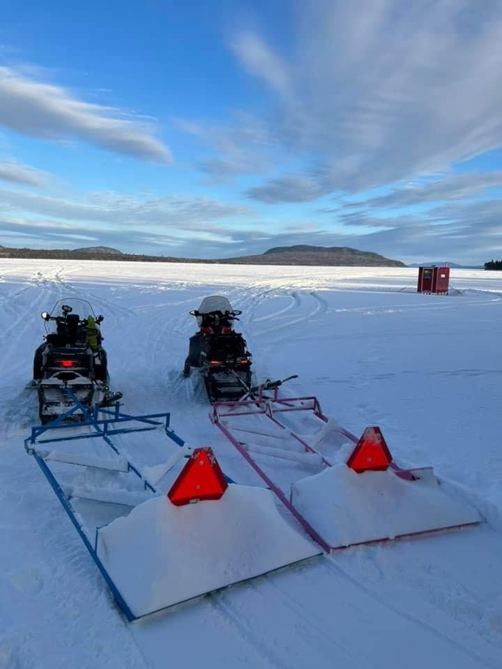 Two snowmobiles are parked next to each other in the snow.