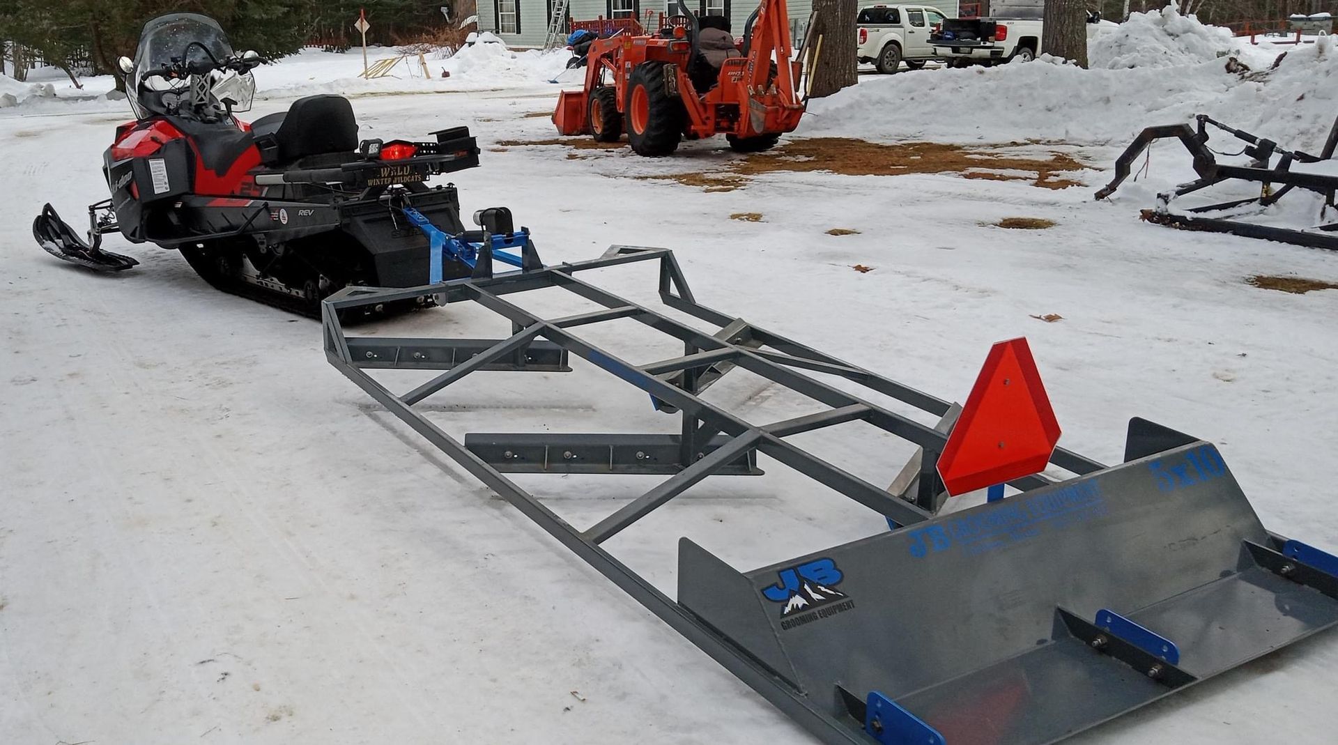 A snowmobile with a trailer attached to it is parked in the snow