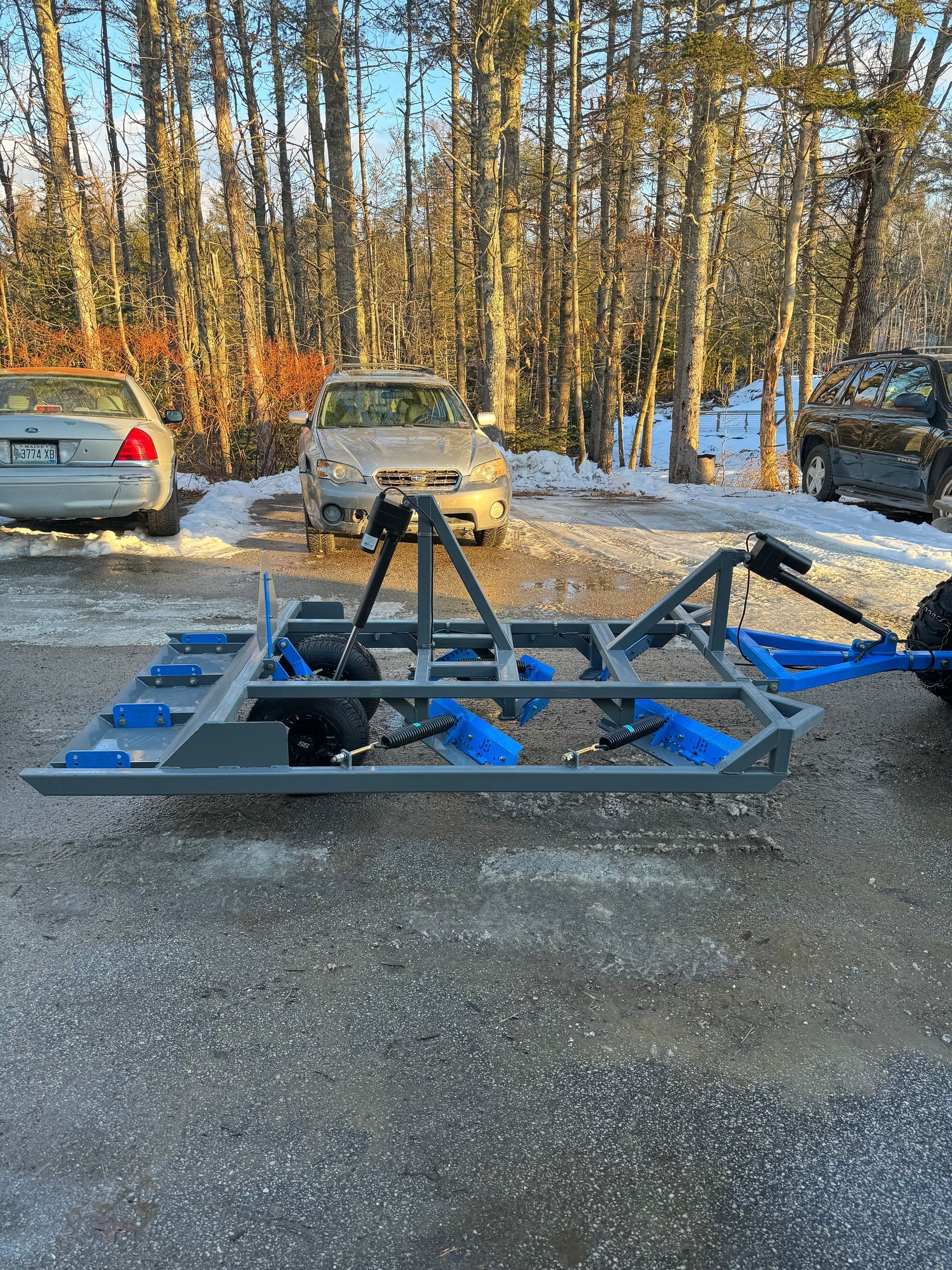 A car is parked next to a trailer in a parking lot.
