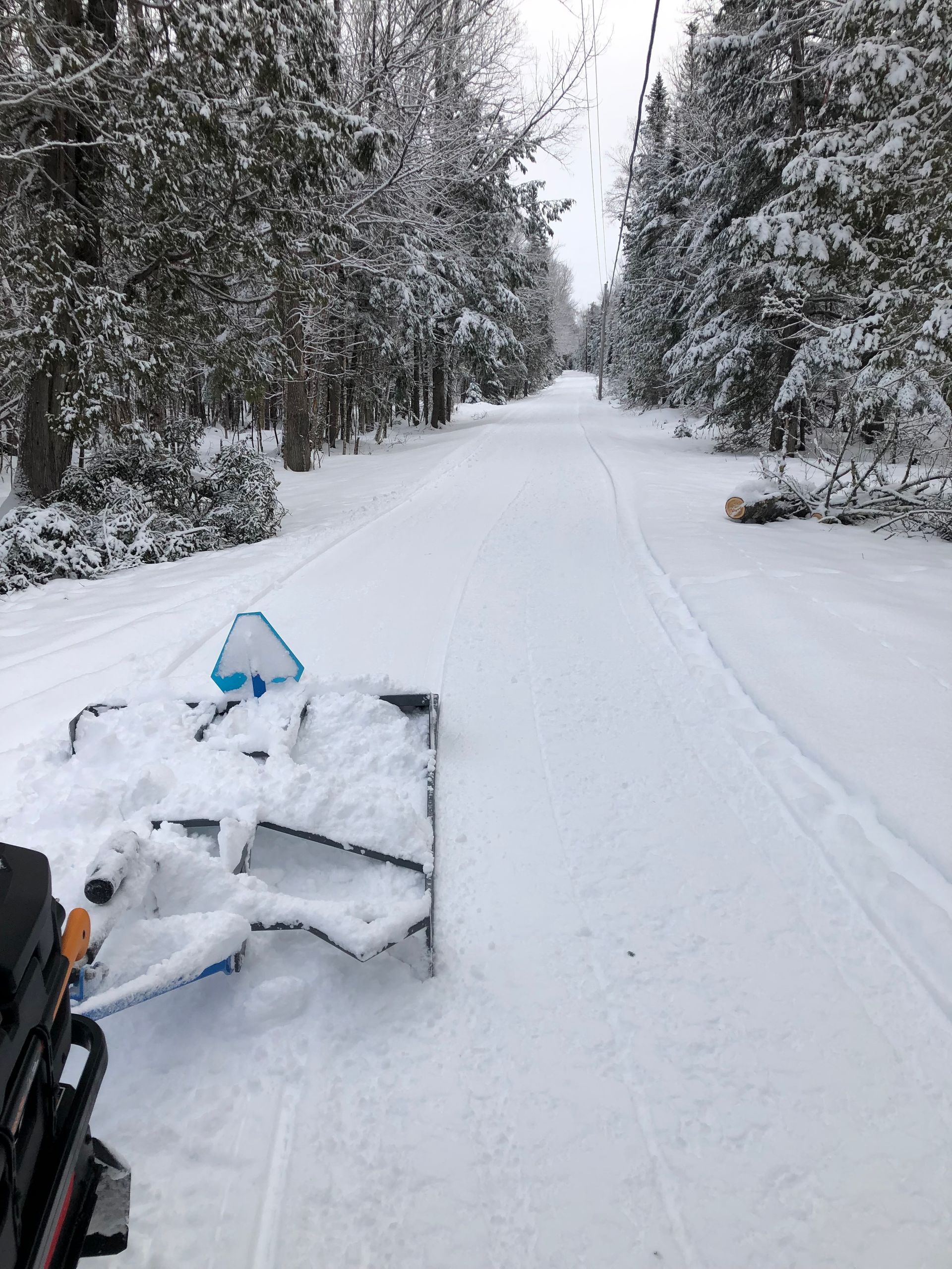 A snowmobile is parked on the side of a snow covered road.