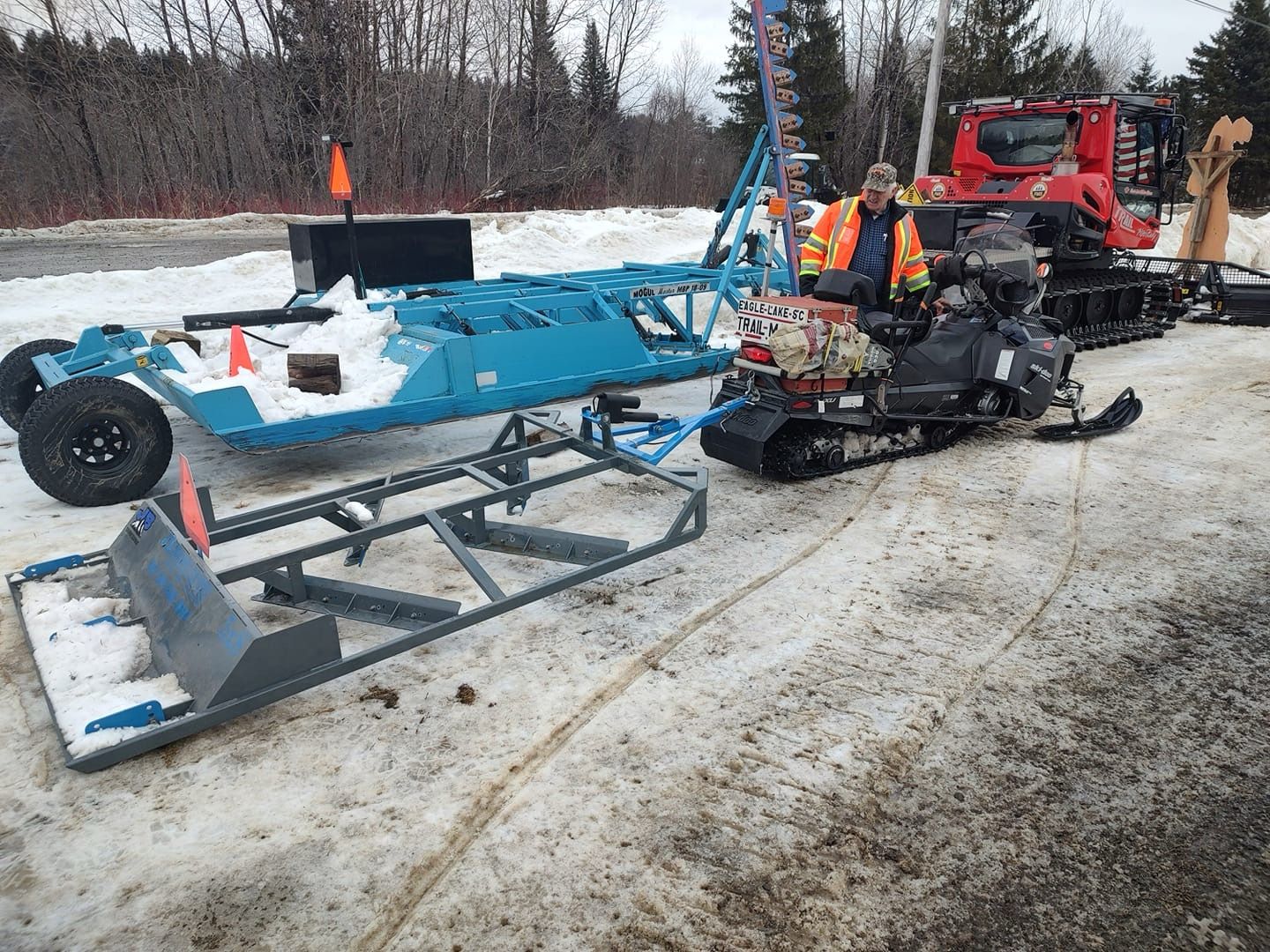 Two snowmobiles are parked next to each other on a snowy road.