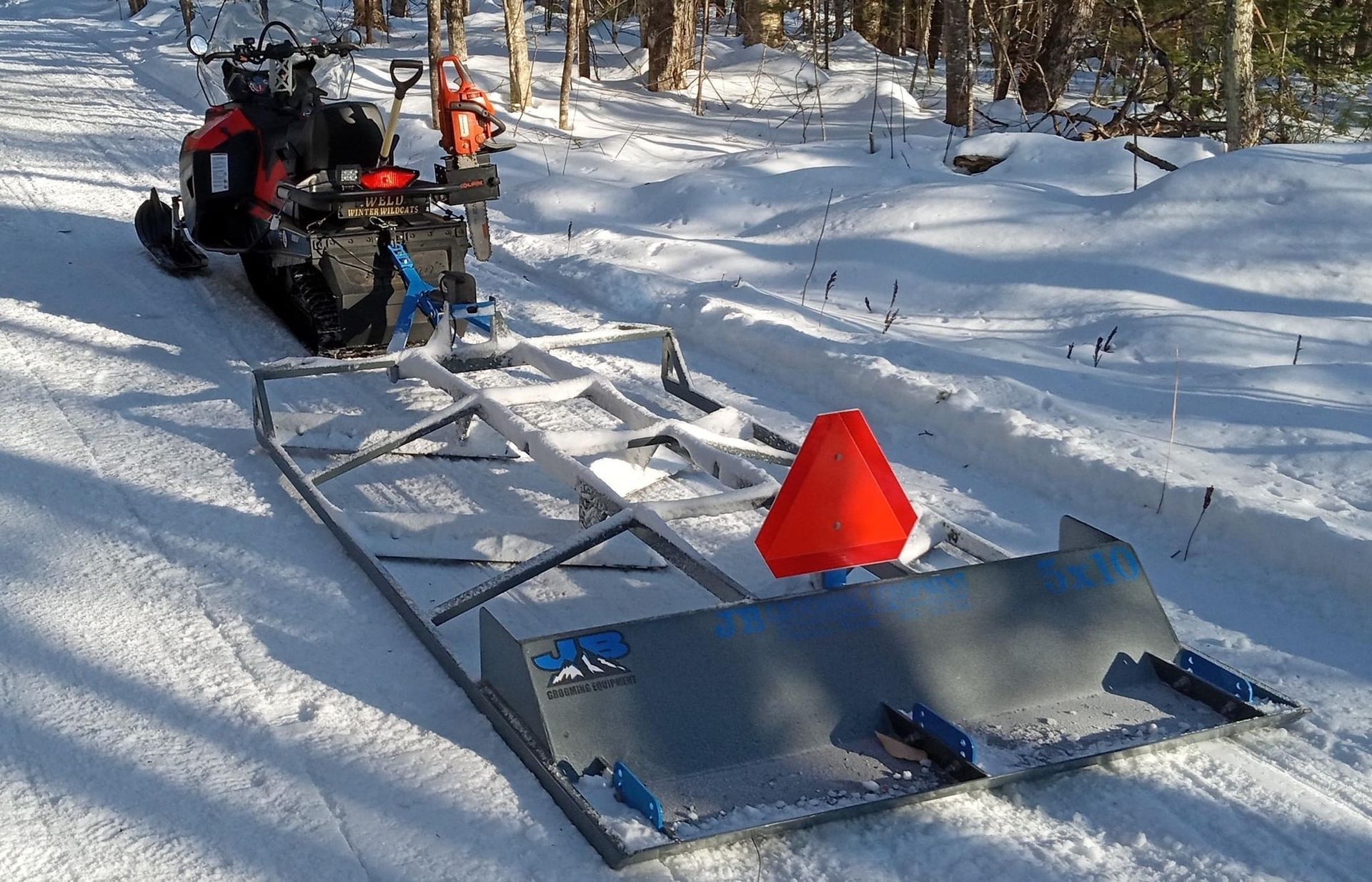 A snowmobile is pulled by a sled in the snow