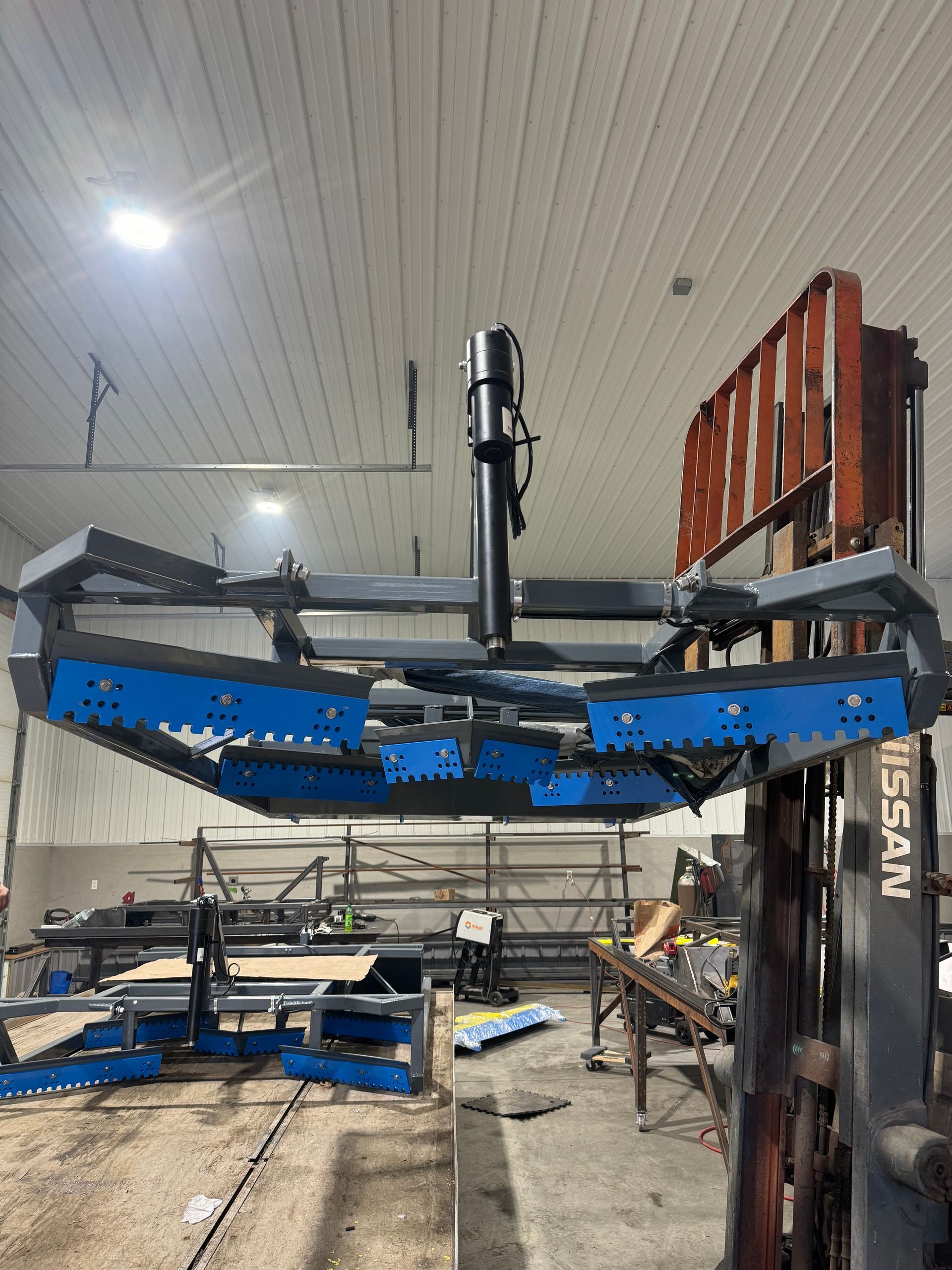 A forklift is sitting in a warehouse next to a large machine.