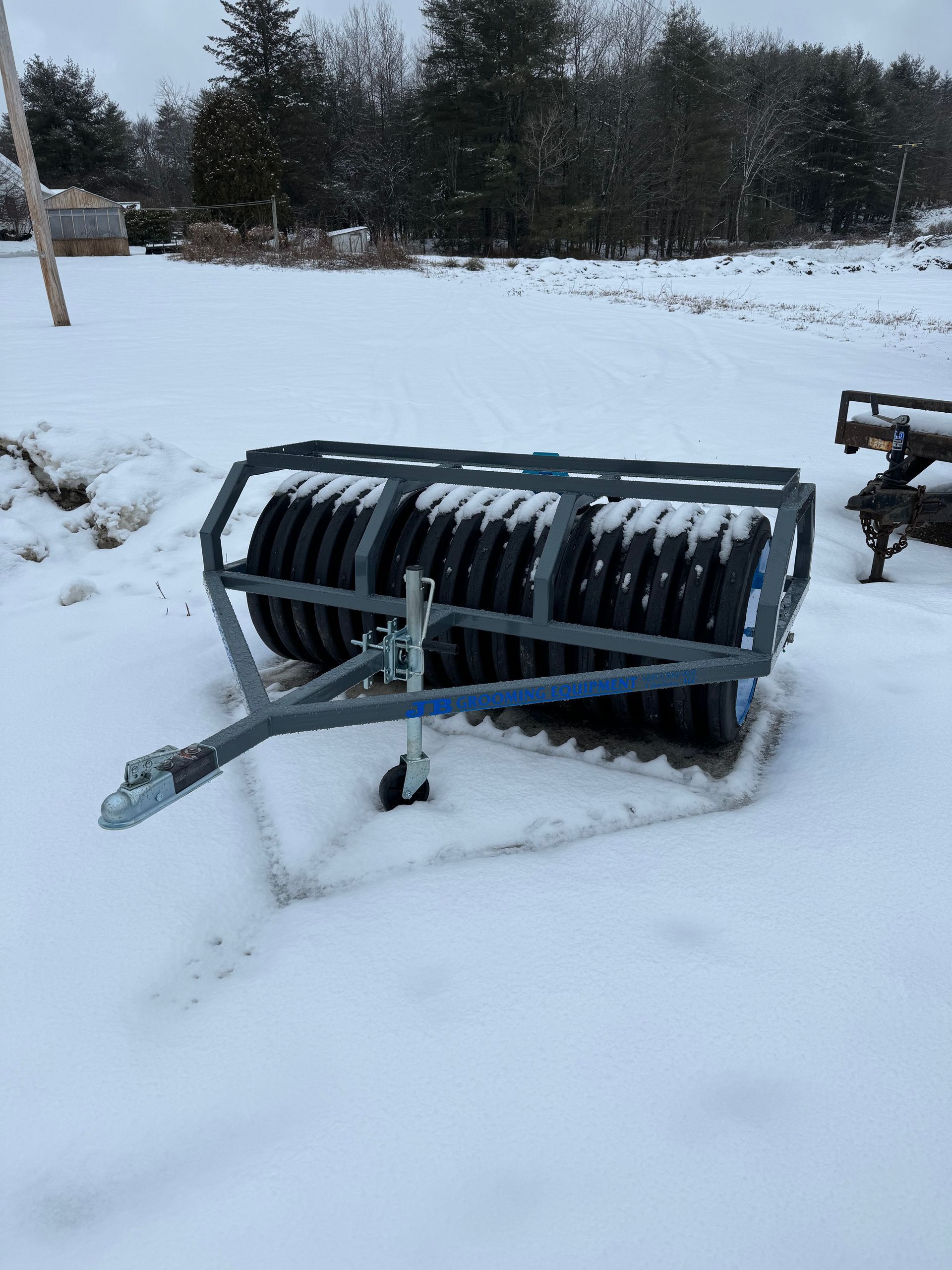 A tire roller is sitting on top of a snow covered field.