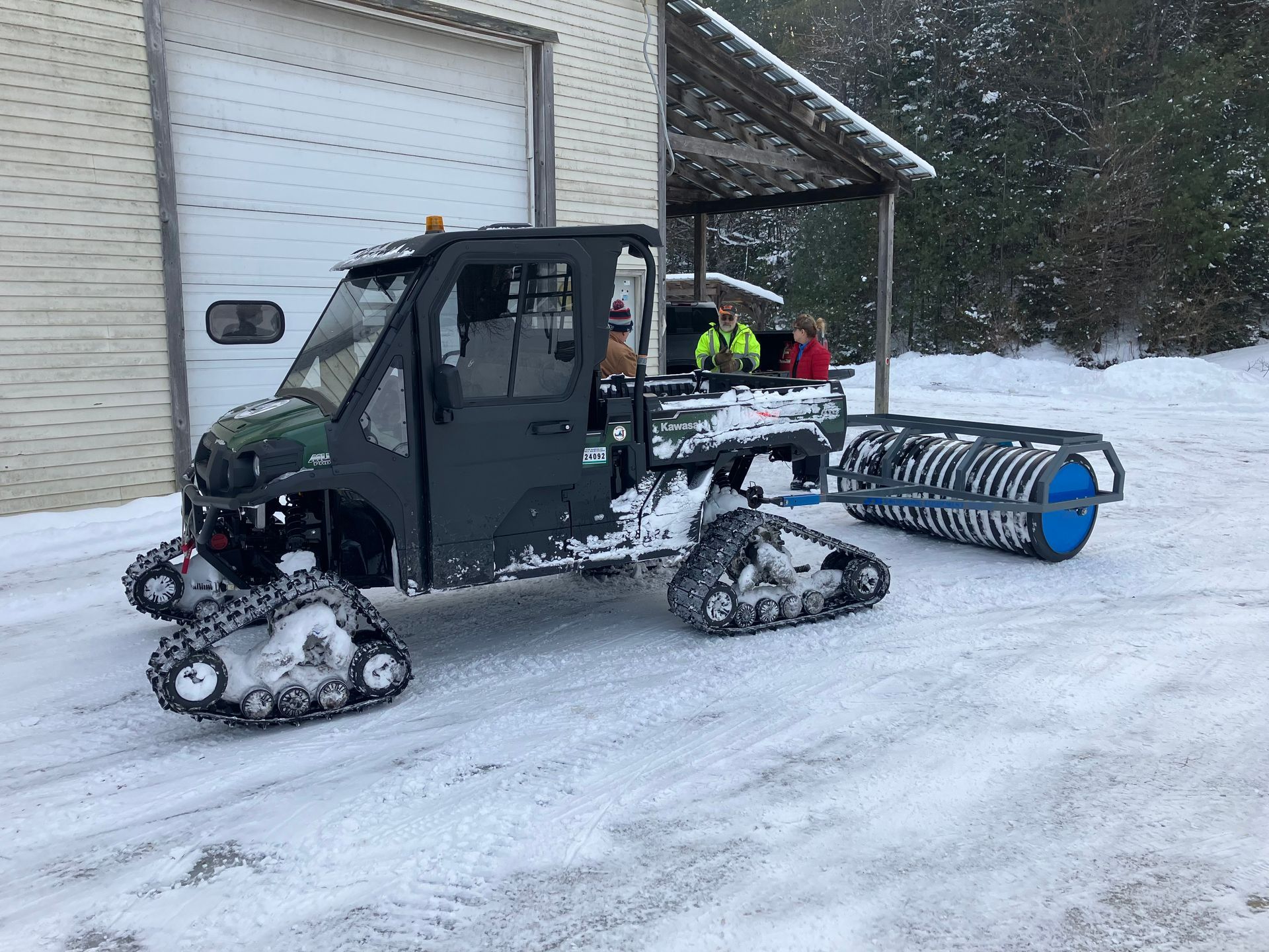 A snowmobile is parked in the snow in front of a garage.