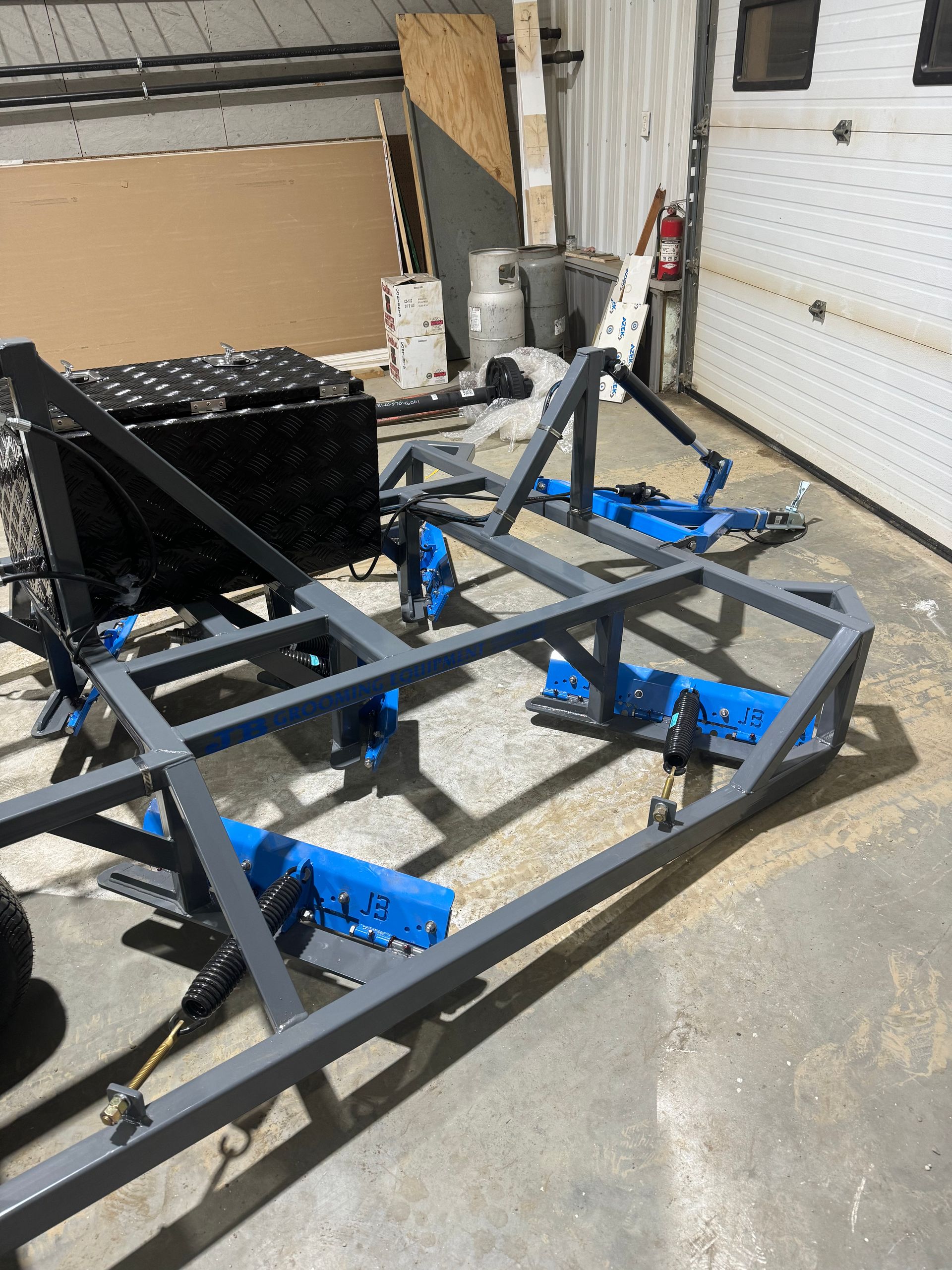 A metal frame with blue wheels is sitting in a garage.