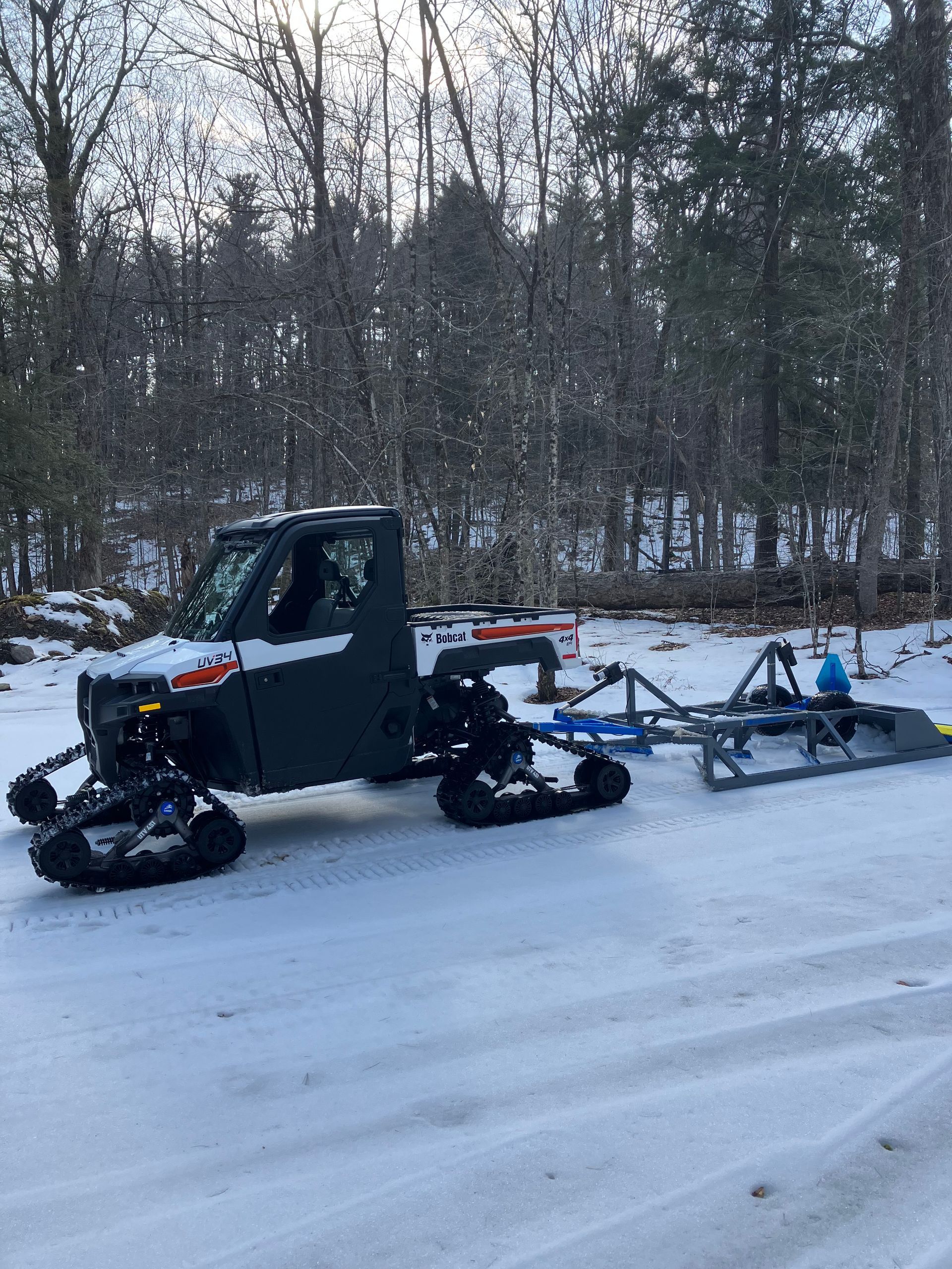 A snowmobile is being pulled by a truck in the snow.