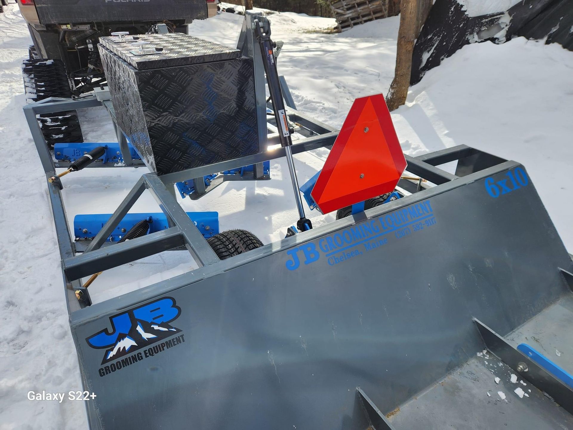 A snowmobile is parked in the snow with a red sign on it.