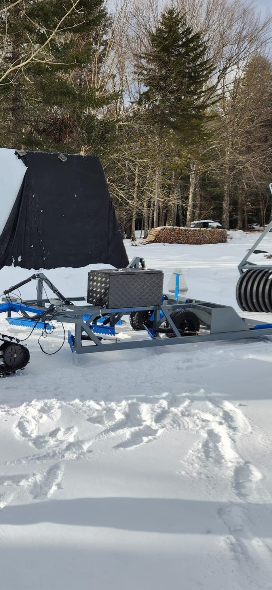 A snowmobile is parked in the snow with a trailer attached to it.