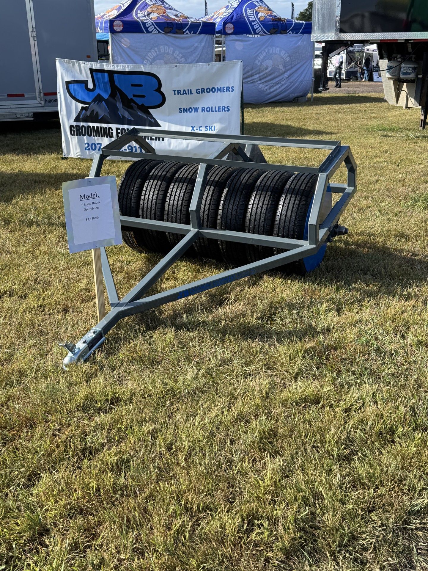 A gray steel tire roller on grass. Sign for 