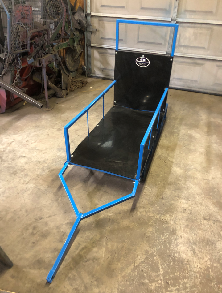 A blue and black sled is sitting on a concrete floor in a garage.