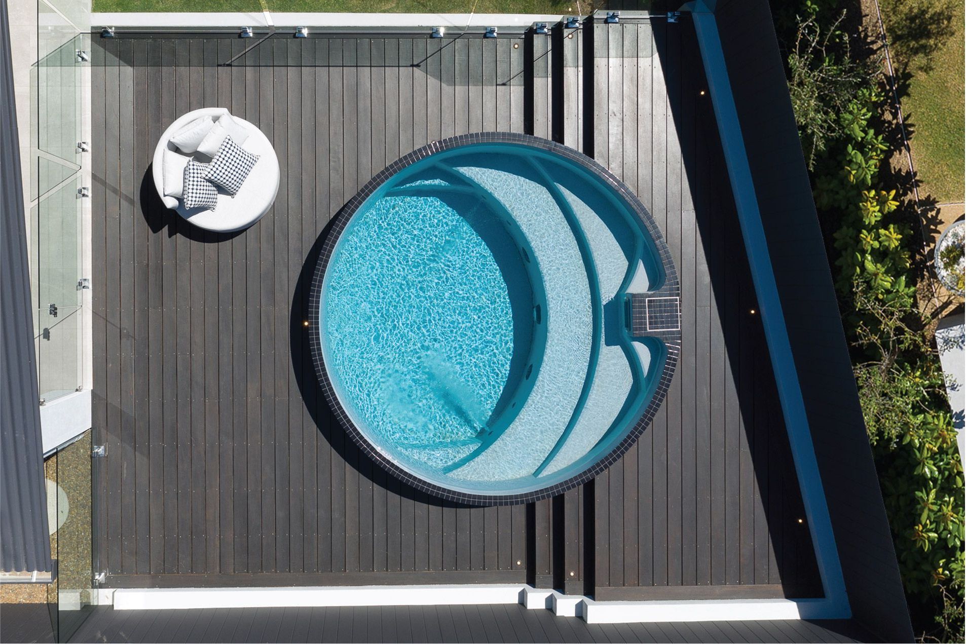 An aerial view of a circular swimming pool, the Plunge Arena on a wooden deck.