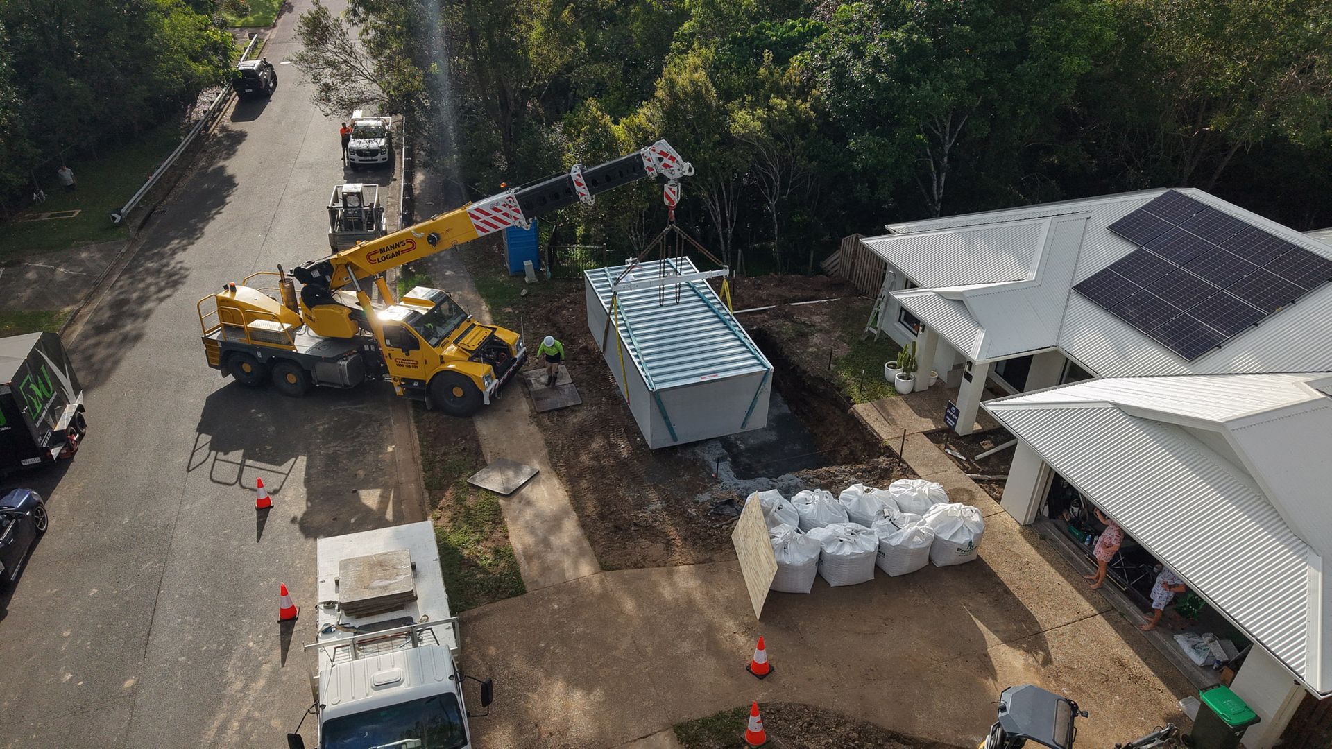 An aerial view of a house being built with a crane installing a precast plunge pool.